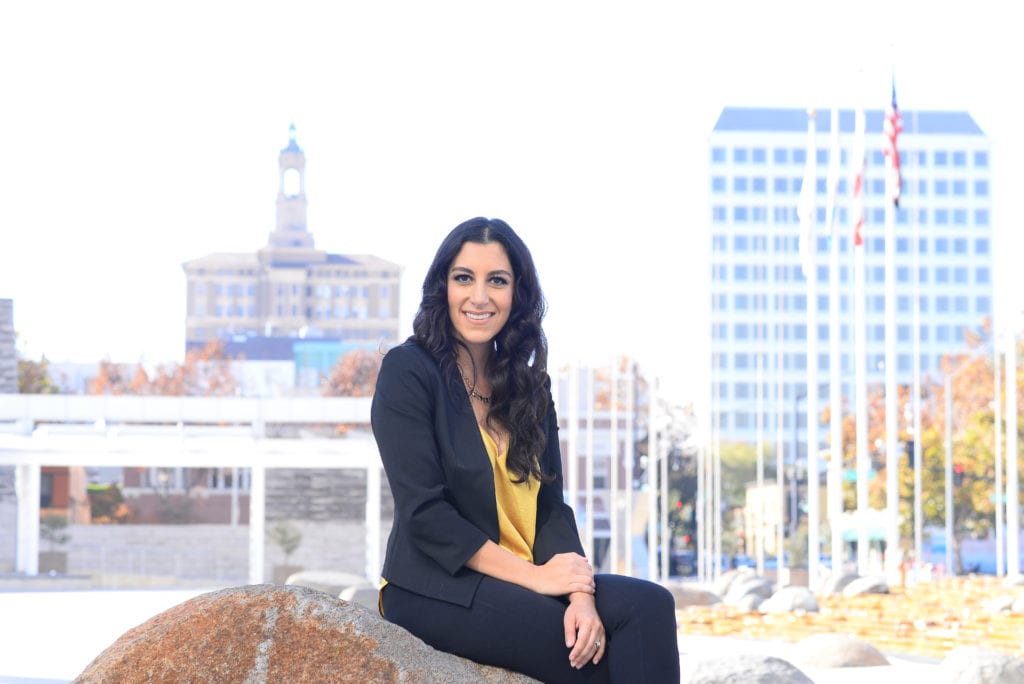 A woman sitting on a boulder outside City Hall in San Jose, California