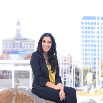 A woman sitting on a boulder outside City Hall in San Jose, California