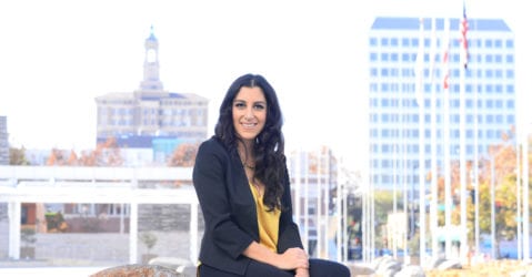 A woman sitting on a boulder outside City Hall in San Jose, California