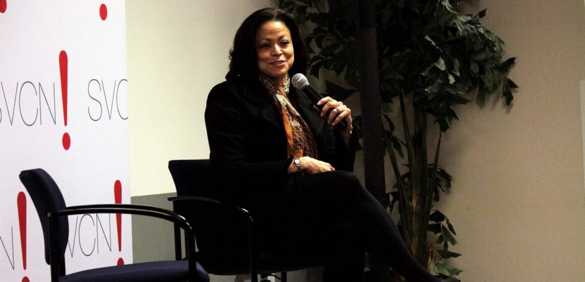 Una mujer sentada en una silla sosteniendo un micrófono.