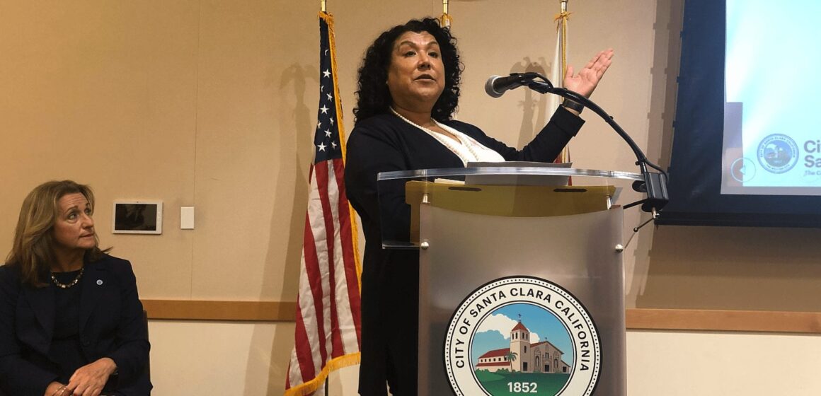 A standing woman speaking at a podium