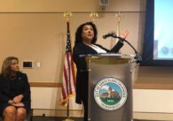 A standing woman speaking at a podium