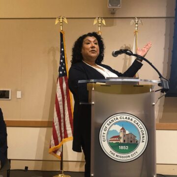 A standing woman speaking at a podium