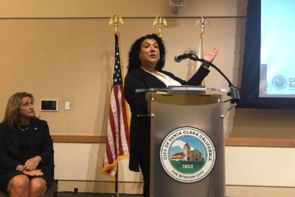 A standing woman speaking at a podium