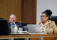 A man and a woman sit behind a council dais
