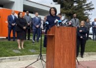 People standingbehind a podium in front of a large building.