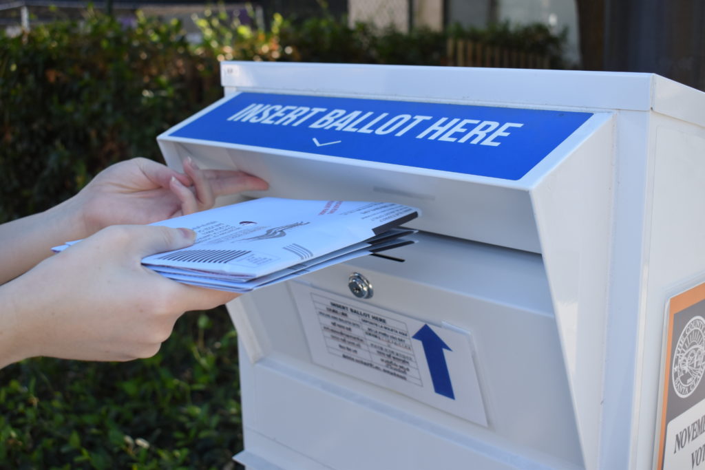 A voter drops off ballots in a neighborhood ballot drop box. Photo by Lorraine Gabbert.