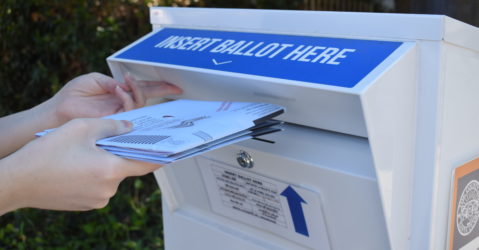 A voter drops off ballots in a neighborhood ballot drop box. Photo by Lorraine Gabbert.