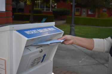 Buzón de boletas Una mano colocando una boleta de voto por correo en una urna segura