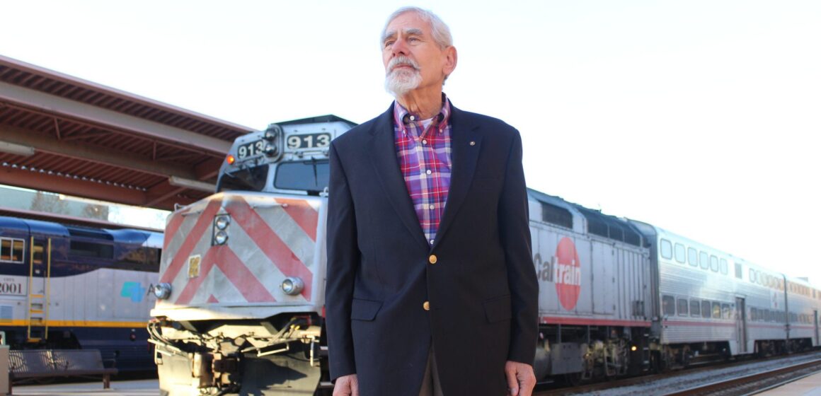 A man stands in front of a train at a station in San Jose, California