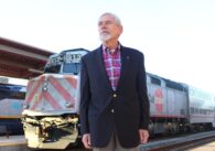 A man stands in front of a train at a station in San Jose, California