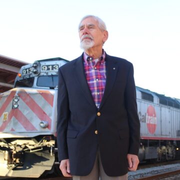 A man stands in front of a train at a station in San Jose, California