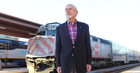 A man stands in front of a train at a station in San Jose, California