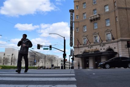 man walking downtown pandemic A person walking across the street in a crosswalk in San Jose, California