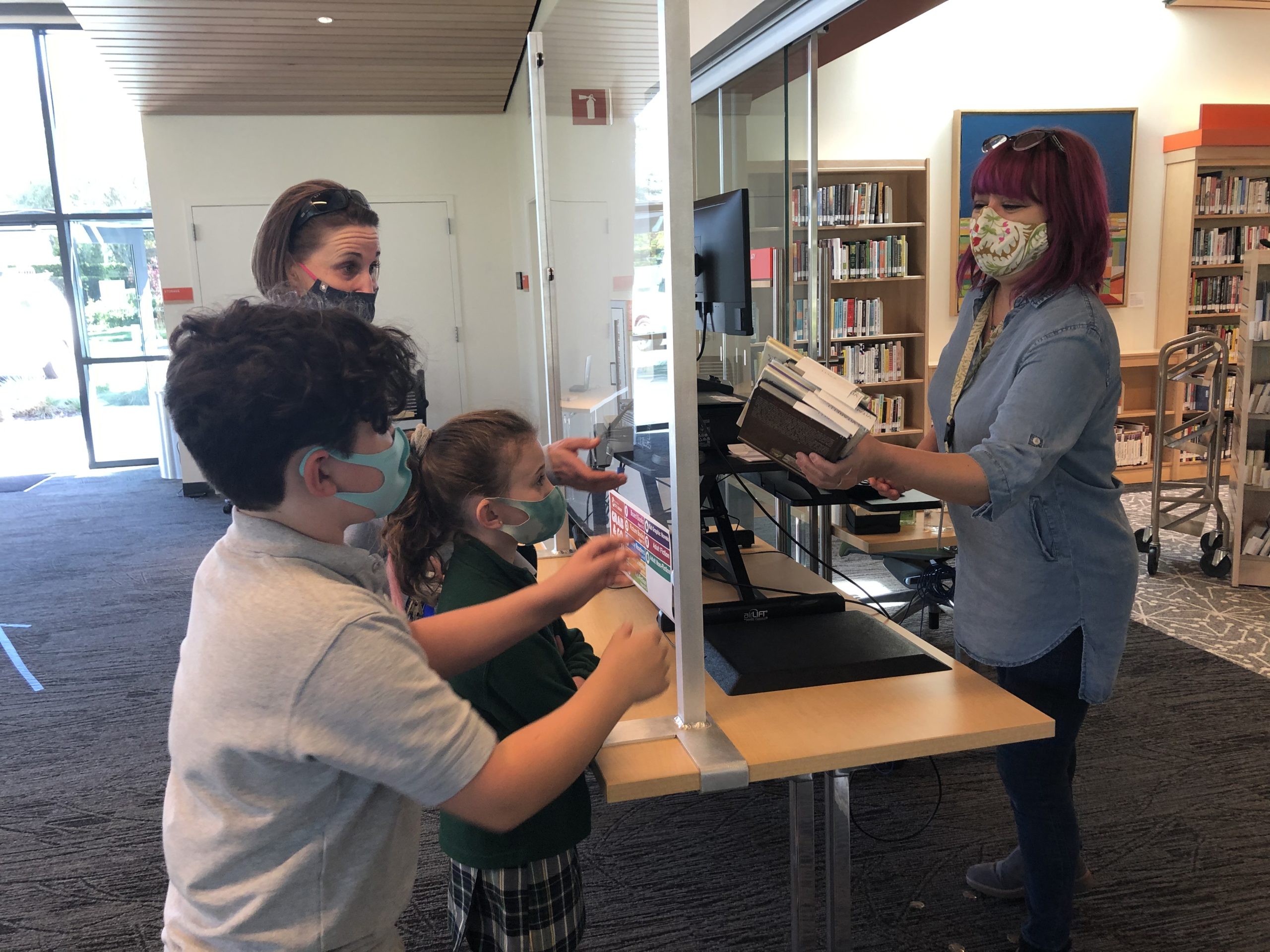 Terra Vitarelli and her children, Luca and Michaela, pick up books placed on hold at the Mission Branch Library in Santa Clara. Photo by Lorraine Gabbert.