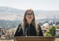 A woman stands outside speaking into a microphone at a podium
