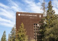 A tall county government building with trees in the foreground