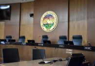 Empty chairs behind a dais in a city council chamber