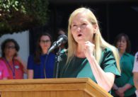 A woman speaks into a microphone at a podium