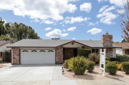 A house with a for sale sign in the front yard