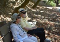 Two older adults sit on a park bench in San Jose