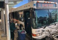 A person with a cart getting onto a bus