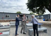 Three men stand outside shaking hands