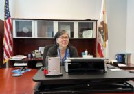 A woman sits behind a desk
