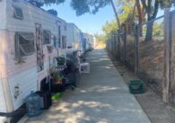 RVs and vehicles parked along a sidewalk near a school.