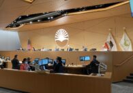 Full Sunnyvale city council seated behind the chamber dais during a meeting, with city staffers seated below.