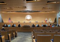 Full Sunnyvale city council seated behind the chamber dais during a meeting, with city staffers seated below.