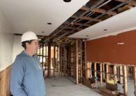 A man wearing a hard hat stands inside a construction project