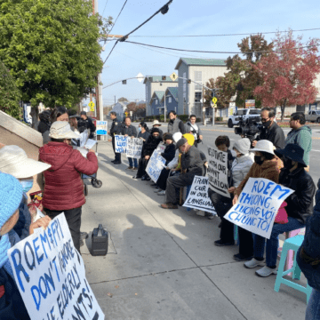 Dozens of seniors sitting on chairs along sidewalk