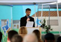 The mayor of San Jose standing at a podium holding a microphone