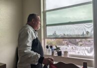 Man looks out his apartment window