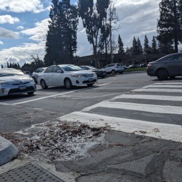 KING ROAD Cars drive through an intersection, behind a crosswalk under a cloudy blue sky.