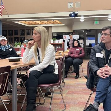 Parents sit in chairs at a school community meeting