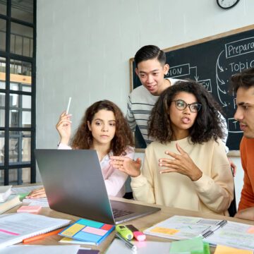 College readiness A diverse group of students in front of a laptop in a classroom.
