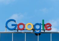 A Google sign on top of a building with blue sky above.