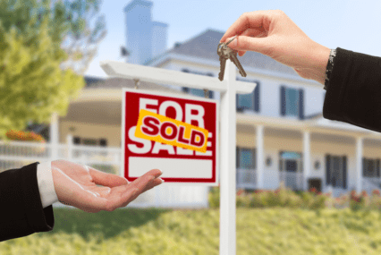 A for sale sign in front of a house that has been sold