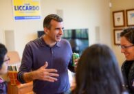 A man stands holding a soft drink while speaking with three women
