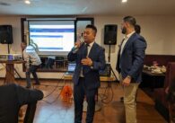 A man in a suit speaks into a microphone