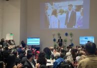 A crowd looks at a man standing at a podium