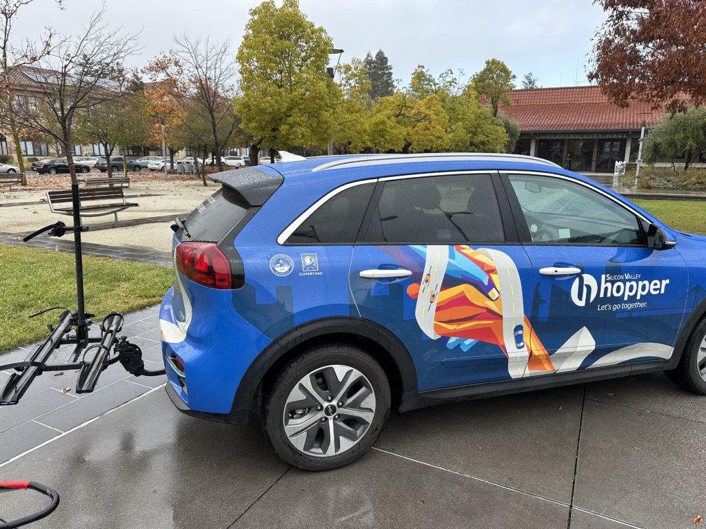 Blue minivan with Silicon Valley Hopper decal and a bike rack on the back
