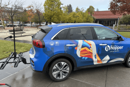 Blue minivan with Silicon Valley Hopper decal and a bike rack on the back