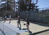 Two pickleball players stand with paddles, readying themselves for the ball on a tennis court with lines taped for the smaller pickleball court at Memorial Park in Cupertino.