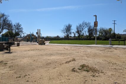 A photo of Sylvia Cassell Park in San Jose, where Councilmember Peter Ortiz said a pirate ship play structure used to be. Visible in photo: A blank gravelly space with a play structure and a slide in the background.
