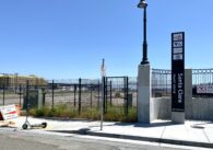The Santa Clara Transit Center sign by the sidewalk, with a fenced-in open plot of land