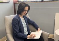A woman sitting in a chair writing in a notebook