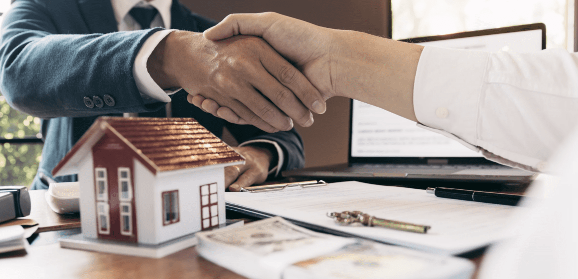 Two people shake hands across a table
